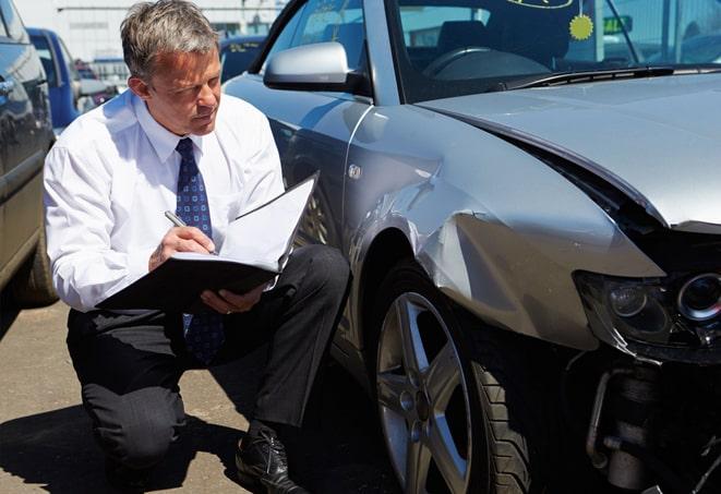 damaged car being inspected by insurance adjuster